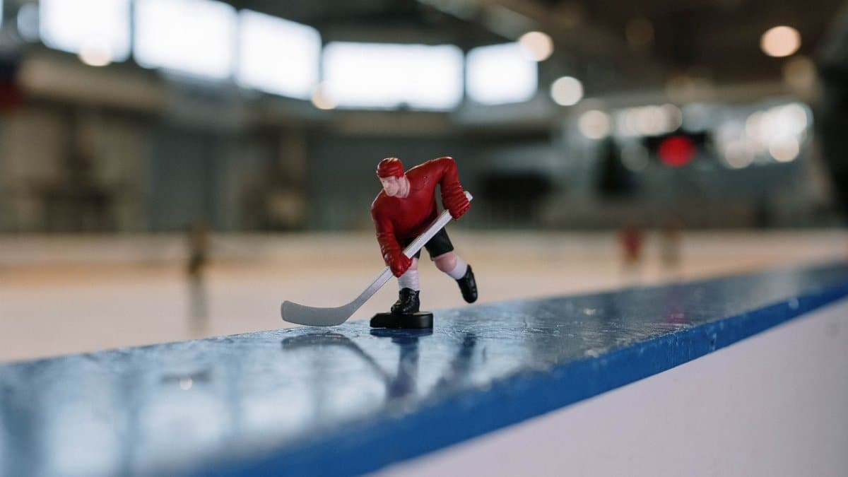Small figurine of a hockey player on a stadium edge, with blurred background.