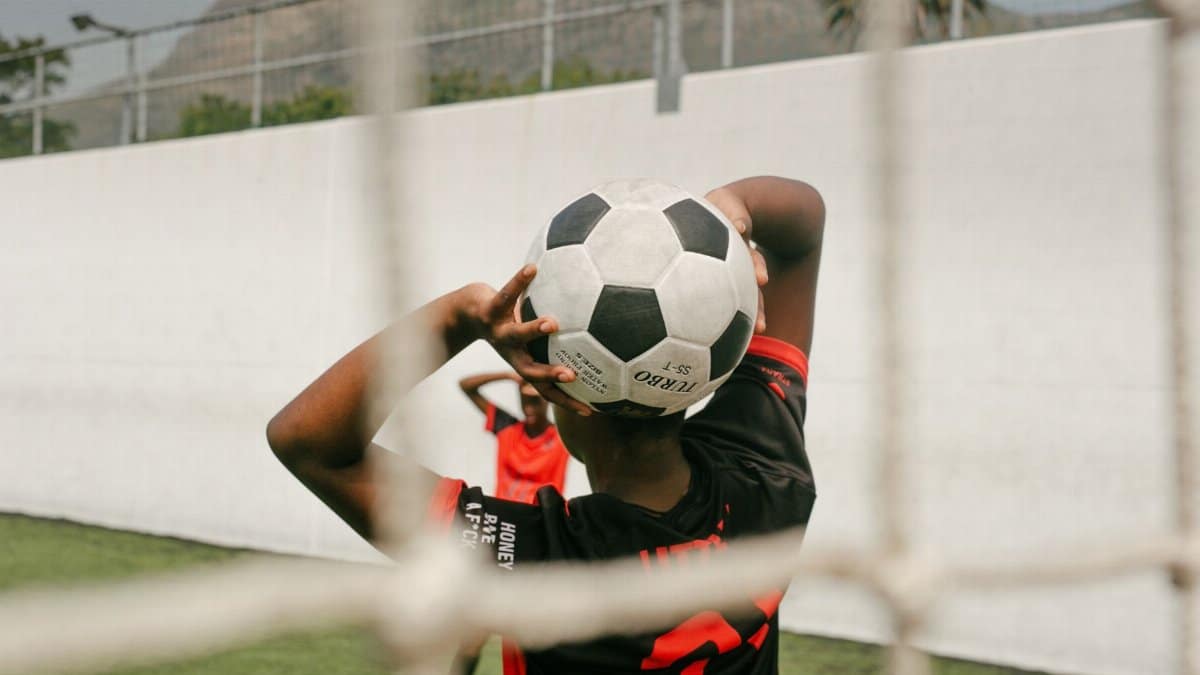 Teen player preparing a throw-in during a soccer match on an outdoor field.