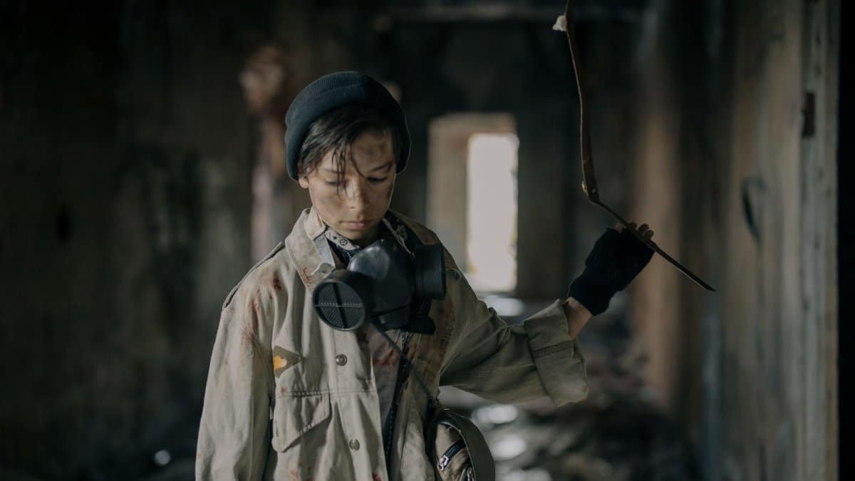 Young survivor with respirator exploring a decaying structure, embodying post-apocalyptic solitude.
