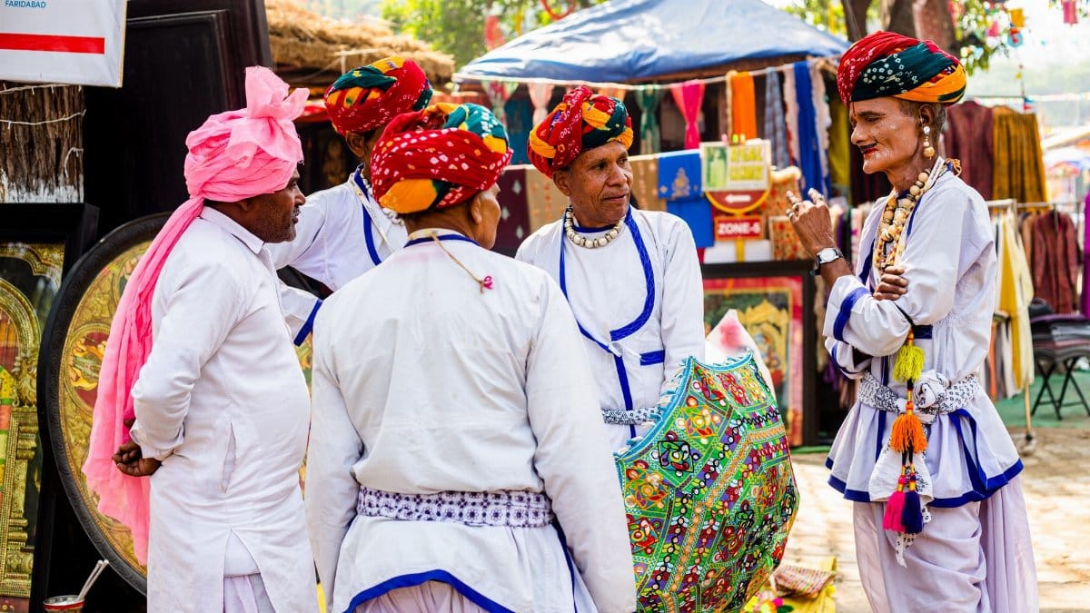 Group of men in vibrant traditional attire with turbans at an Indian cultural festival.