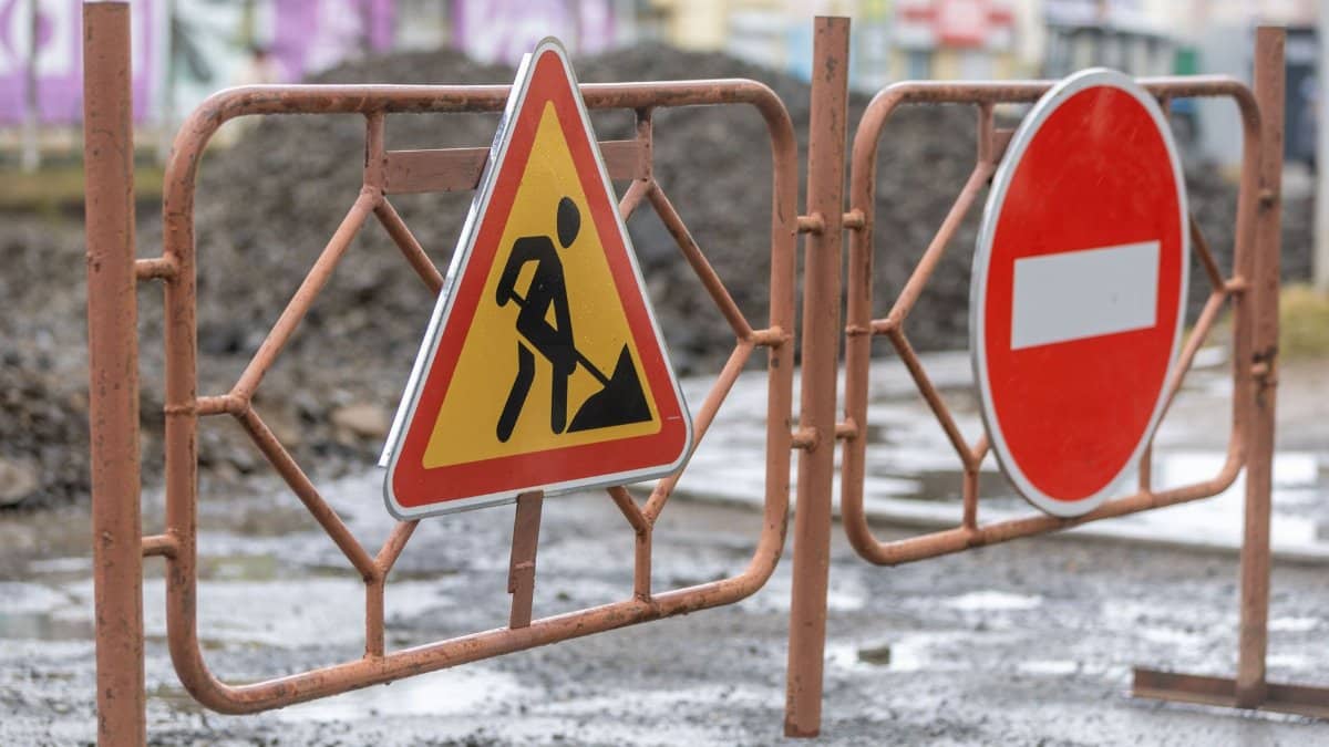 Traffic signs indicating a construction zone and no entry on a rainy day.
