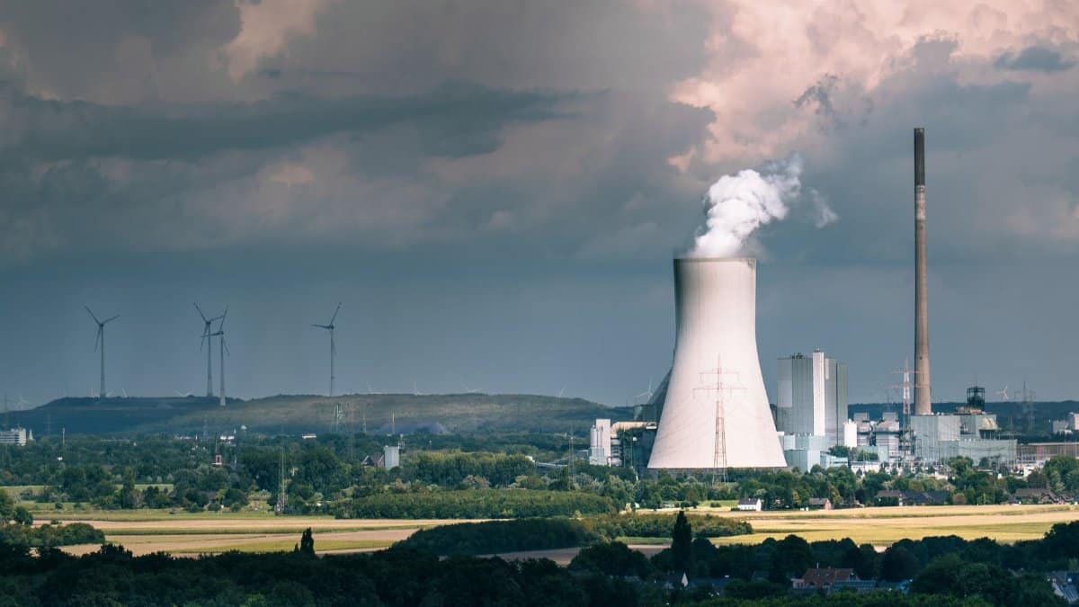 Aerial view of a power plant with steam rising, set against a dramatic sky in Duisburg, Germany.