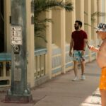 Two men walking on a sunlit street in Miami, Florida, showcasing vibrant summer fashion.