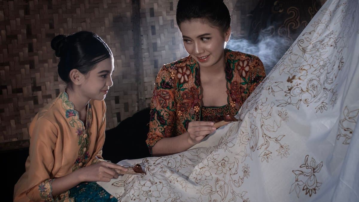 Two people crafting batik cloth with intricate designs in Bandung, Indonesia.