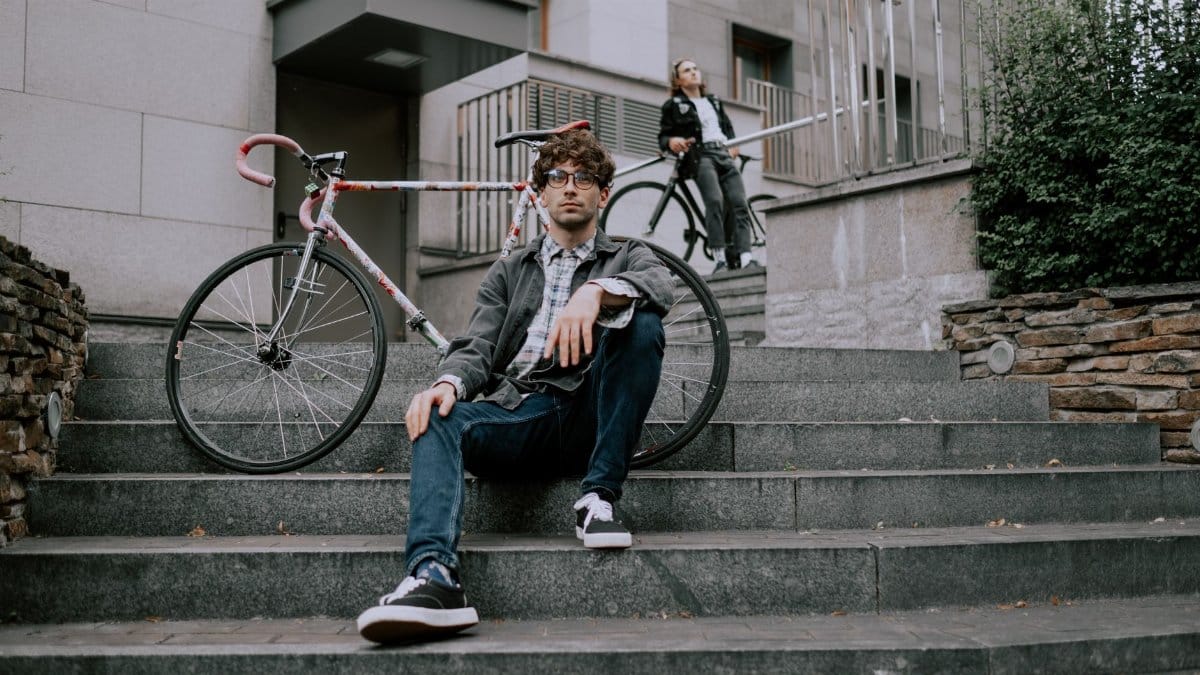 Two men with bicycles on city steps, showcasing urban cycling lifestyle.