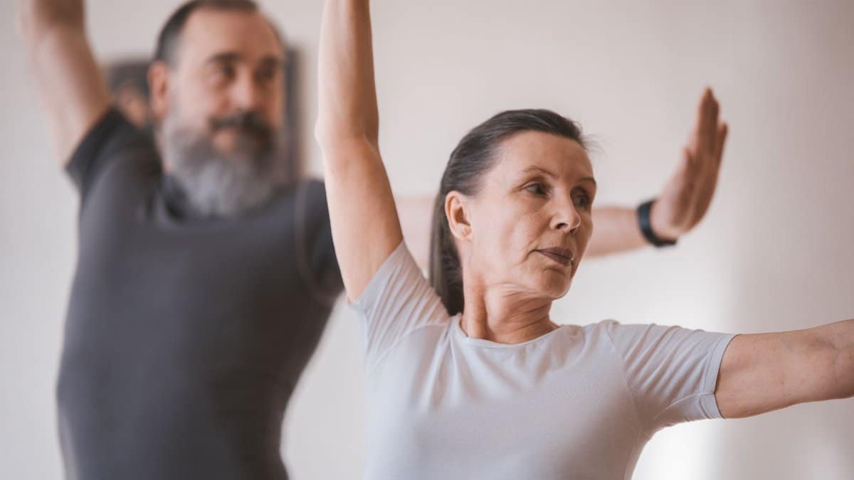 Senior adults in a yoga session indoors, focusing on stretching and balance.
