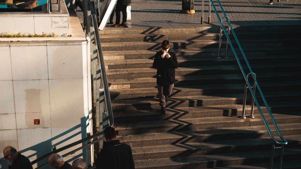 A group of people moving down steps in an urban setting, casting long shadows.