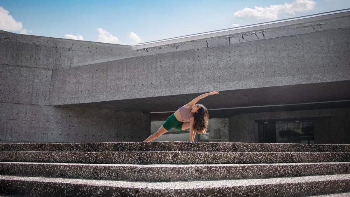 Woman performing yoga pose on stone steps in Ciudad de México, blending fitness and urban architecture.