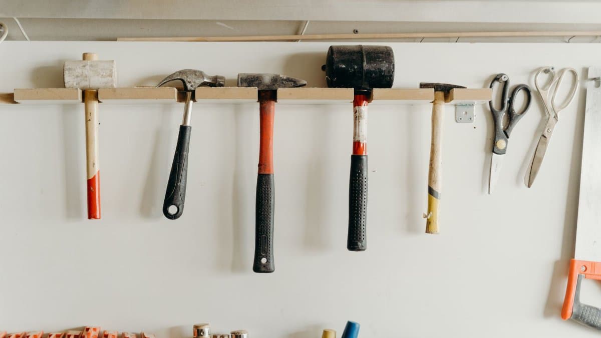 Neatly organized tools hanging on a workshop wall, including hammers and scissors.