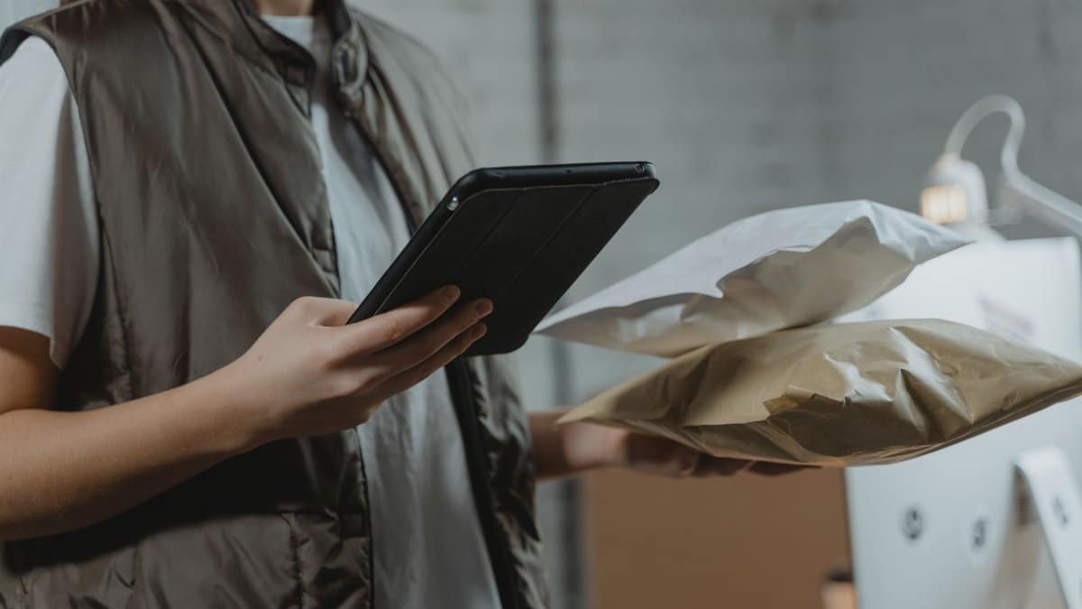 A person using a tablet to manage packages in an indoor setting, highlighting technology and logistics.