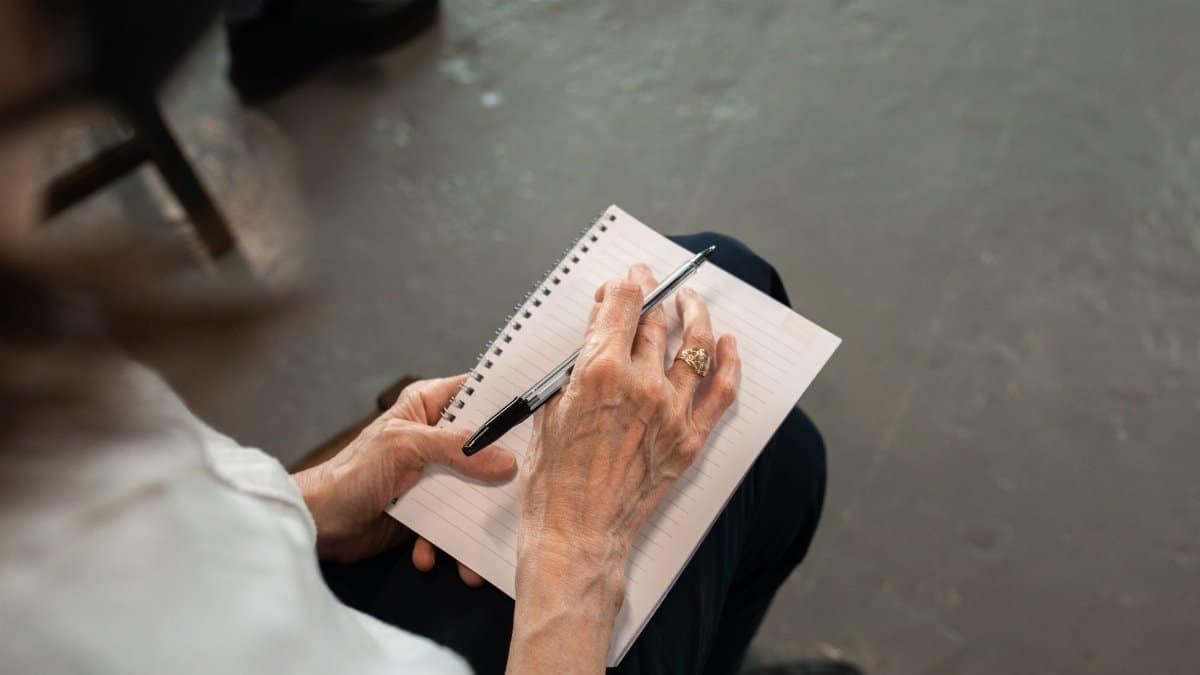 Close-up of senior hands with pen writing in a spiral notebook. Personal notes concept.