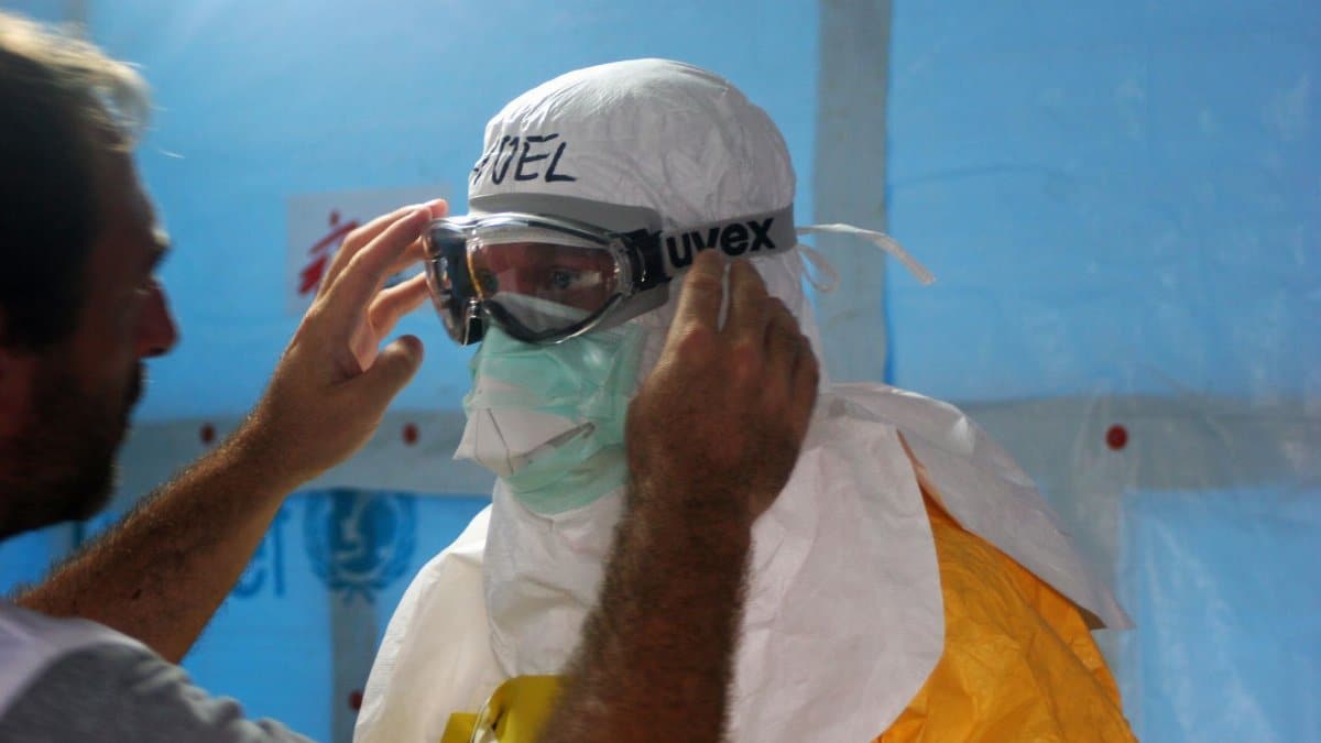 Healthcare worker puts on PPE gear in a medical facility for safety and protection.