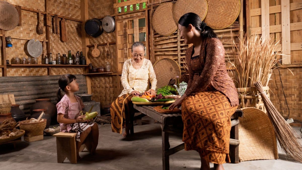 Three generations cooking together in a traditional bamboo kitchen setting.