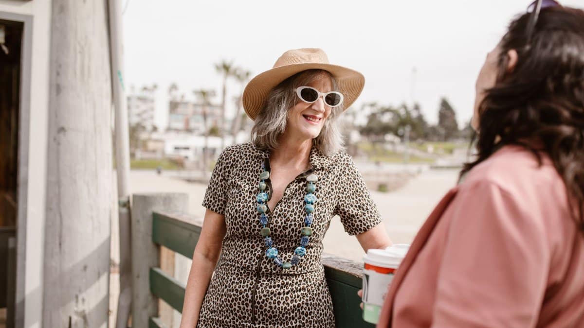 Two stylish women chatting outdoors, showcasing summer fashion and joy.