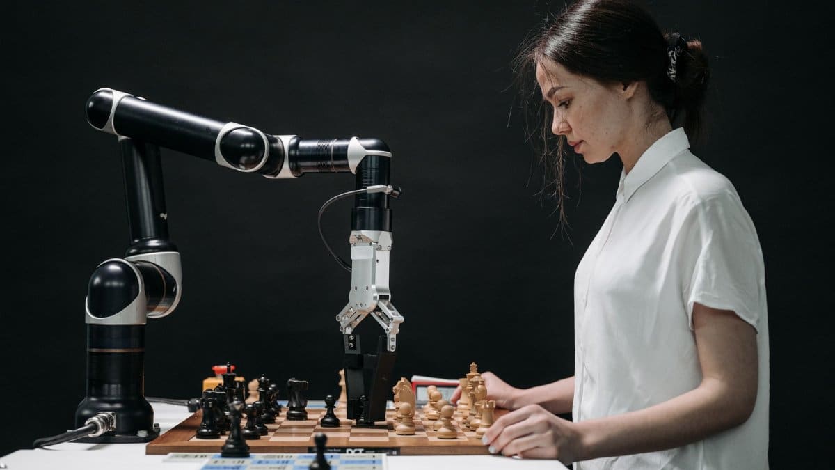 A robot and woman engage in chess, showcasing technology and strategic thinking.