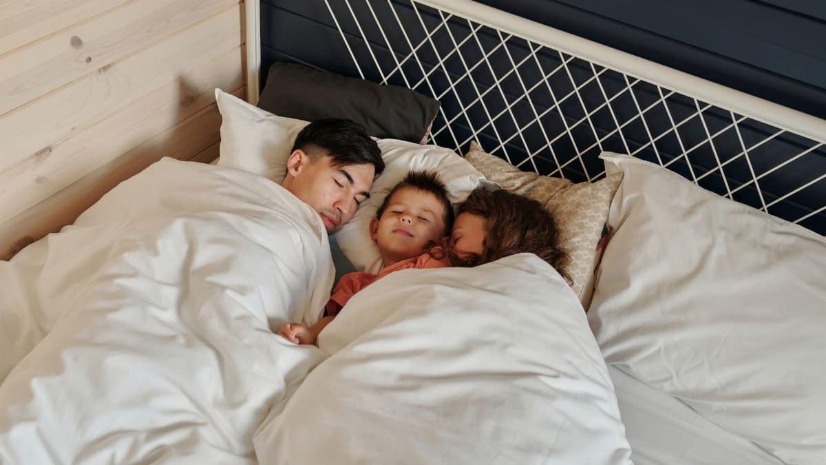 A family peacefully sleeping together in a cozy bedroom setting, showcasing warmth and togetherness.