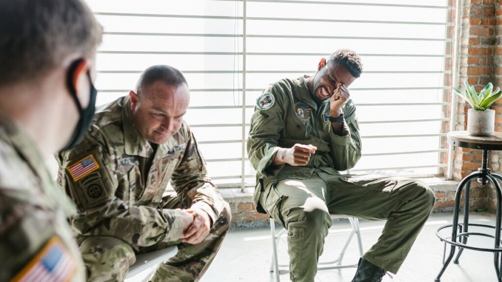 Veterans share a light moment during a group therapy session, indoors.