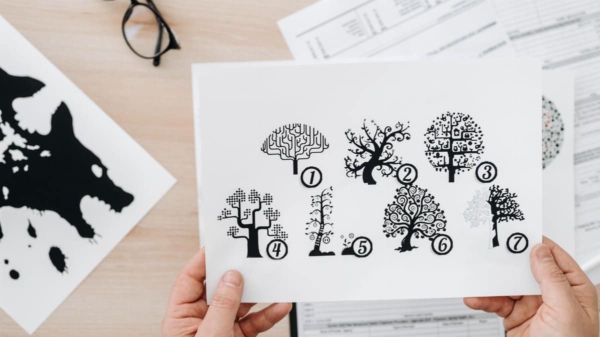 Close-up showing hands holding paper with tree test illustration for psychological assessment.