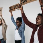 A diverse group of adults holding protest signs indoors, advocating against violence.