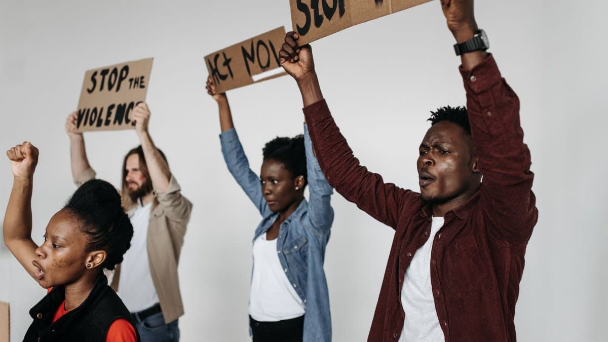 A diverse group of adults holding protest signs indoors, advocating against violence.