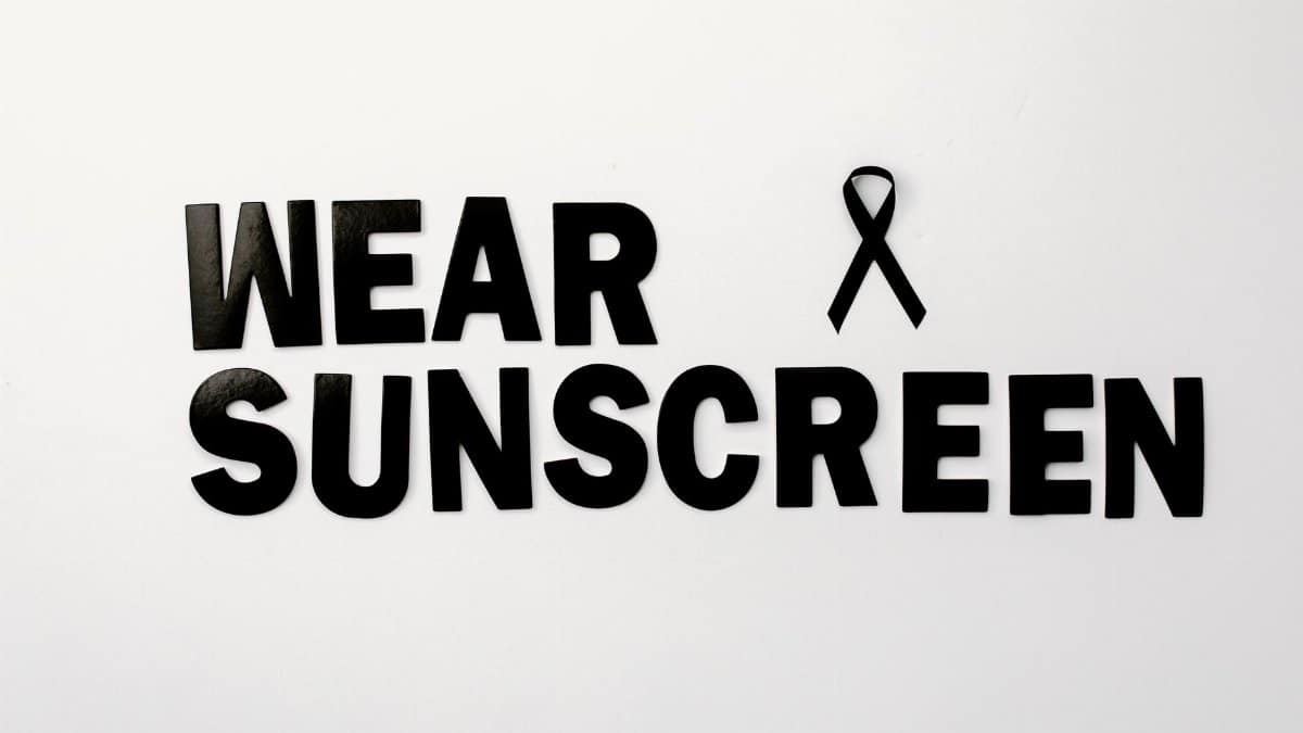 Black text and ribbon promoting skin cancer awareness with a sunscreen message.