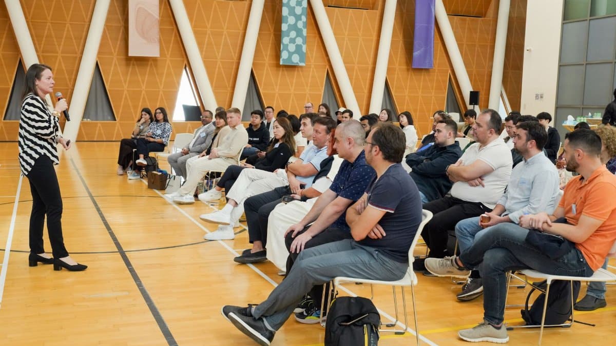 Speaker presenting to attentive audience in a modern hall with triangular decor.