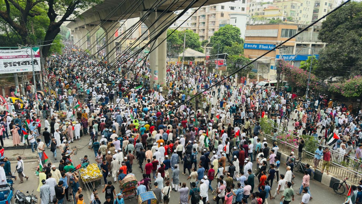 Large crowd gathered for a street protest under an overpass in Dhaka city.