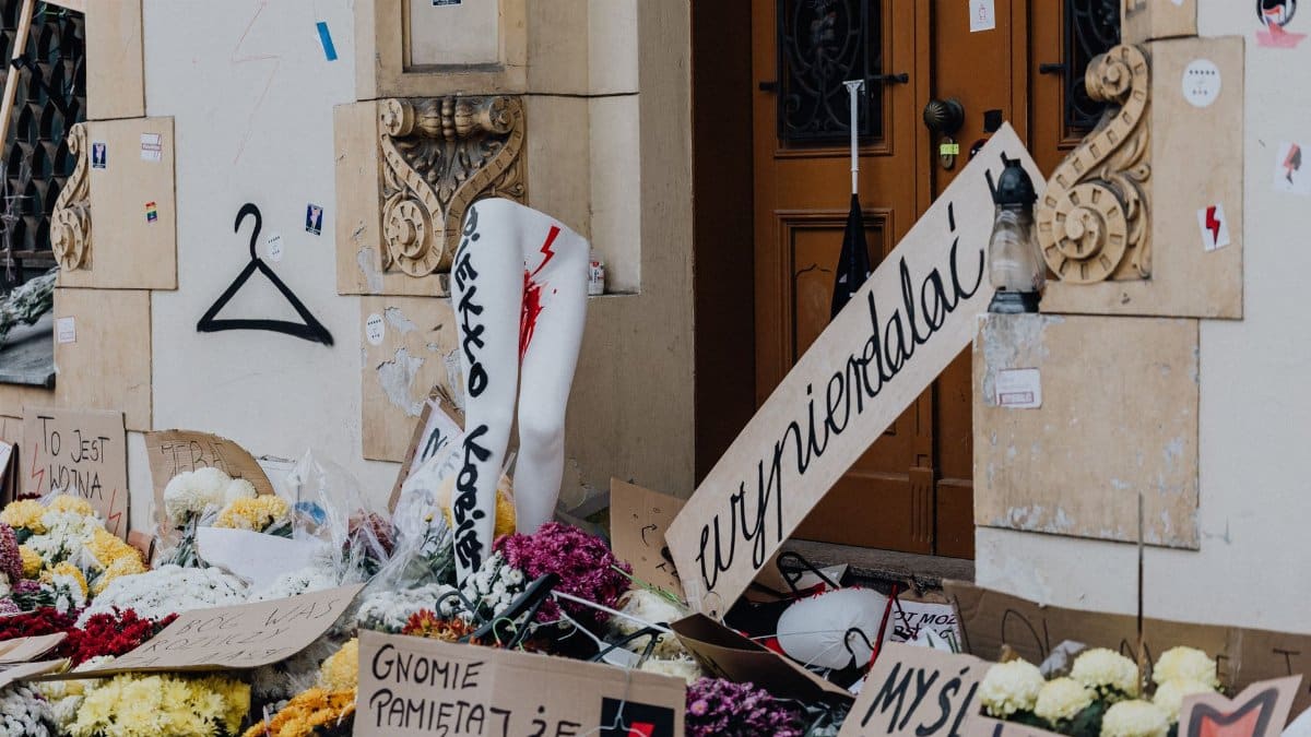 Urban protest scene with flowers and handwritten signs in front of a building, reflecting social activism and public sentiment.