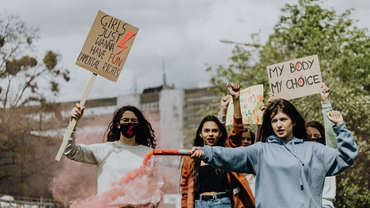 A diverse group of women protesting outdoors holding signs advocating for women's rights and freedom.