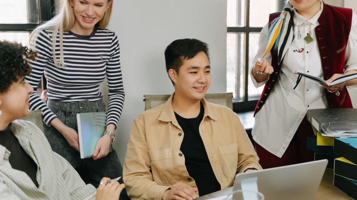 A diverse group of young professionals collaborating in a modern office setting, engaging in teamwork and discussion.