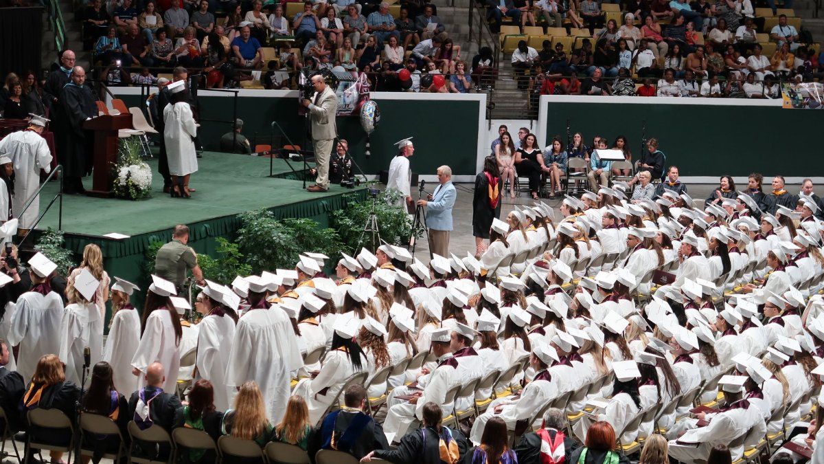 A large graduation ceremony with students in caps and gowns gathered indoors at Hammond, LA.