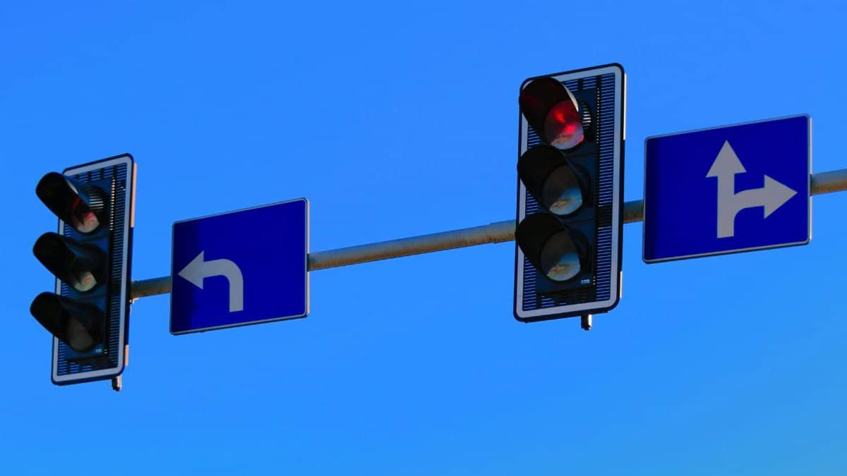 Traffic lights and directional road signs on a clear day with blue skies.