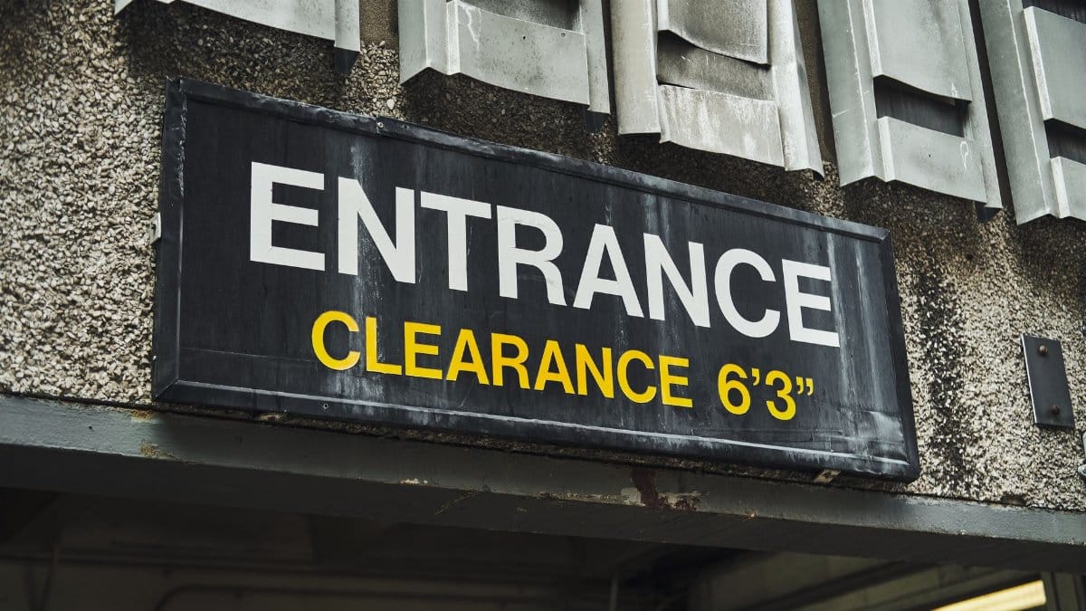 Close-up of an entrance clearance sign on a building, indicating height limit.