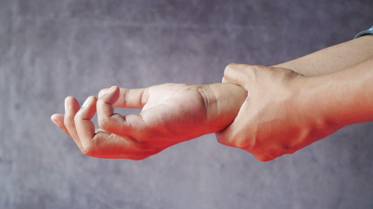 Close-up of hands, one grasping the other, symbolizing pain or discomfort.