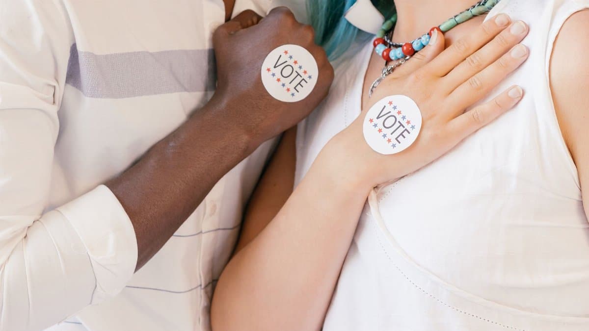 Close-up of two diverse individuals showing their commitment to voting with stickers.