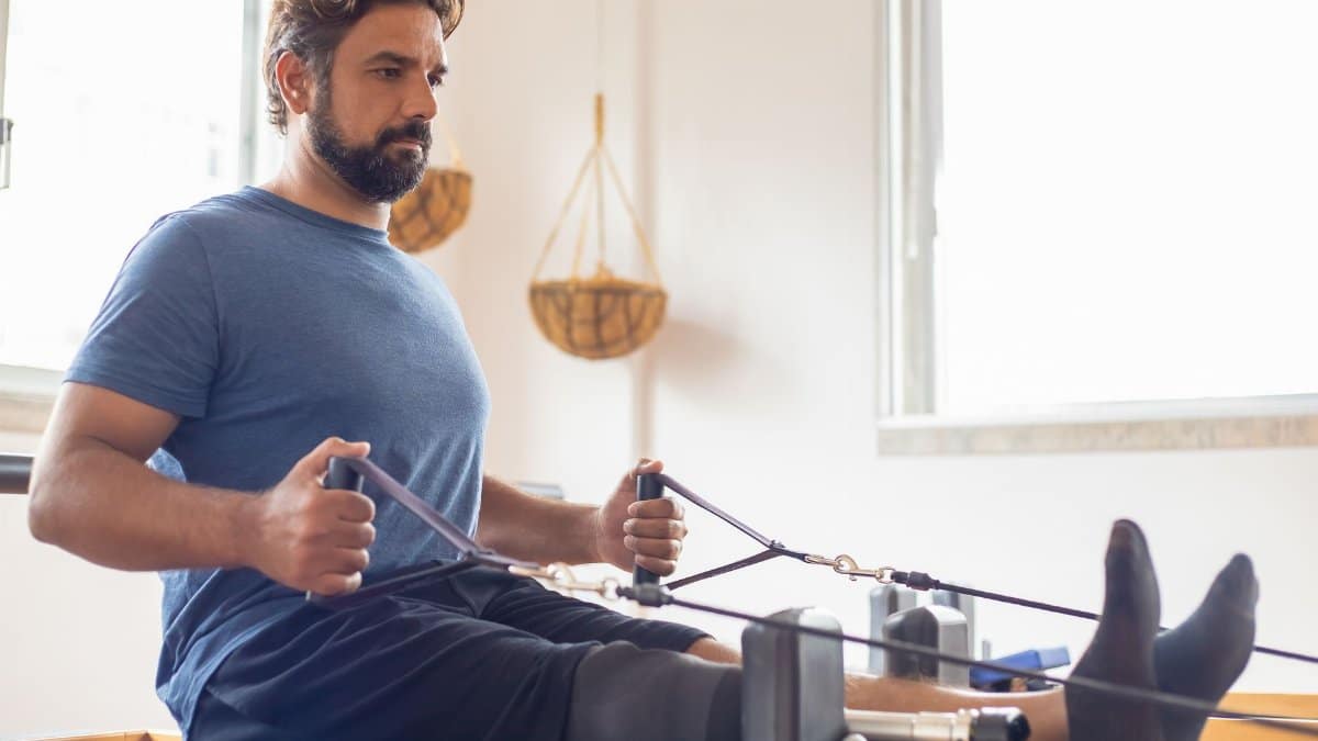 Man with prosthetic leg performing pilates rehabilitation indoors, focusing on strength and recovery.