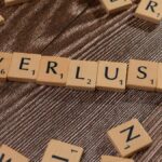 Scrabble tiles spelling 'Verlust' on a wooden table, symbolizing loss or financial context.