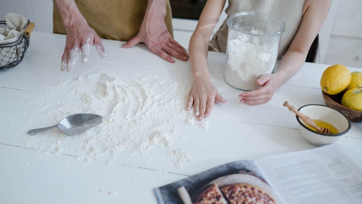 A father and daughter engage in baking, surrounded by flour, lemons, and ingredients, creating a warm family moment.