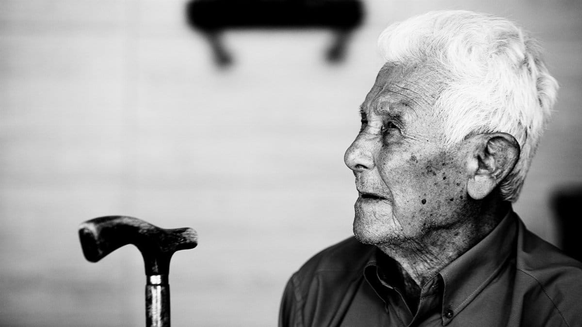 Elderly man in profile holding a cane, captured in black and white for timeless impact.