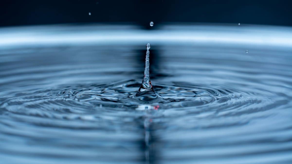 Detailed shot of a water droplet causing ripples, showcasing liquid dynamics.