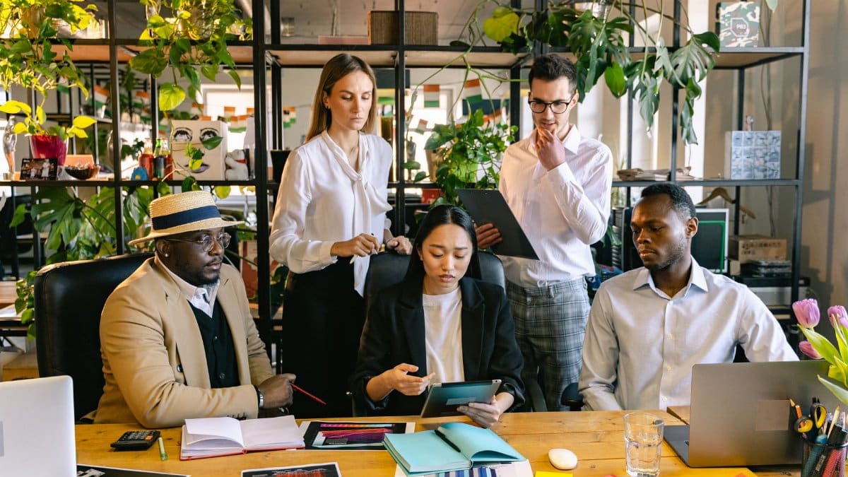 A diverse team of professionals collaborating on a project in a lively office setting.