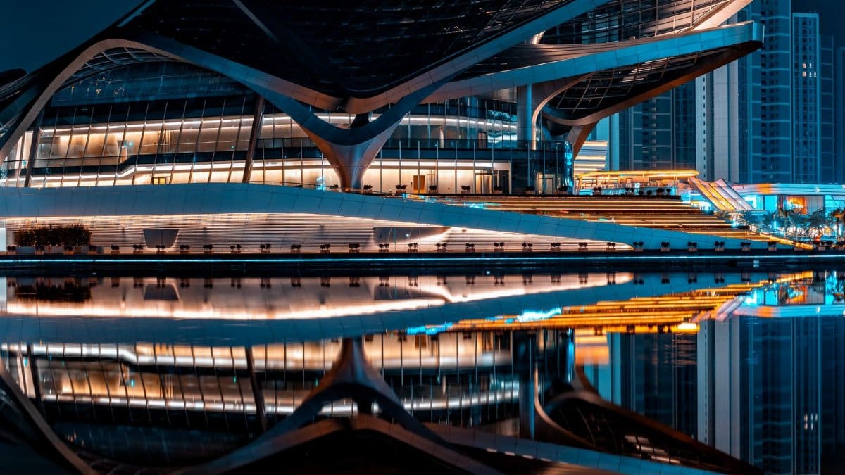 Futuristic building with striking reflections on water at night, showcasing modern architectural design.
