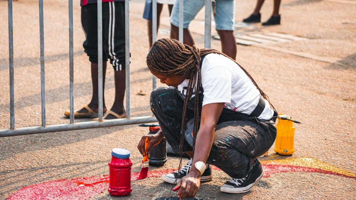 A talented street artist paints a vibrant mural in Accra, showcasing creativity and culture.