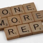 Scrabble tiles arranged to spell 'One More Rep', symbolizing fitness motivation.