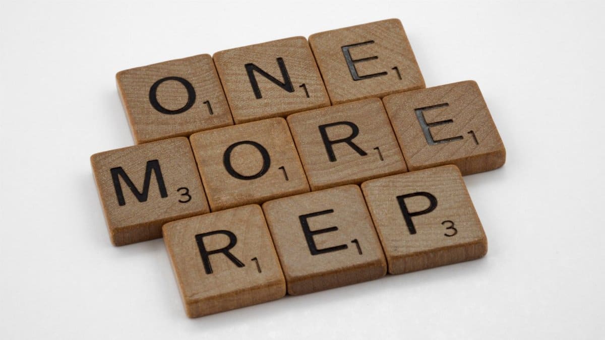 Scrabble tiles arranged to spell 'One More Rep', symbolizing fitness motivation.