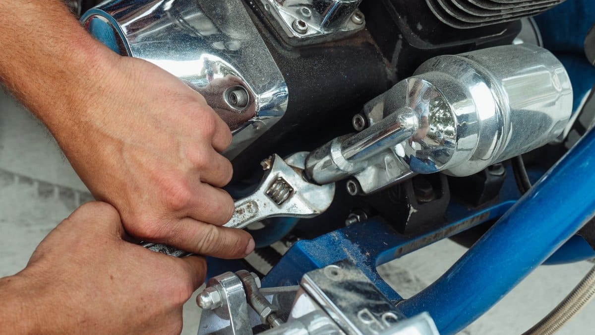 Close-up of a mechanic's hands using a wrench to repair a motorcycle engine.