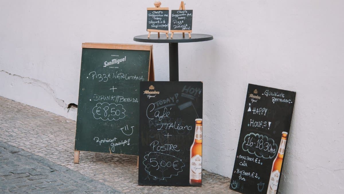Outdoor chalkboard menus with drink offers and Italian cuisine at a Málaga restaurant.