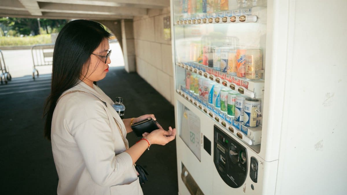 Woman interacts with a vending machine outdoors under a bridge in Taiwan.
