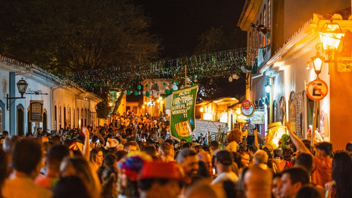 A bustling festival street scene in Tiradentes, Brazil, filled with lights and joyful revelers.