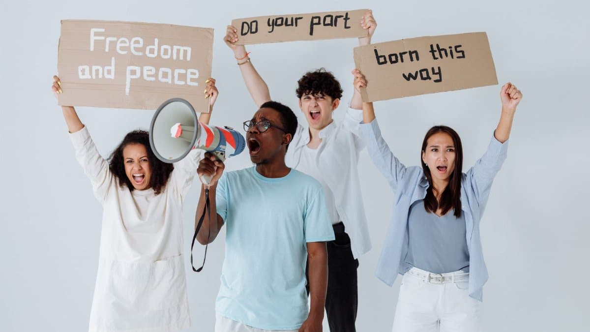 Diverse group of adults holding protest signs advocating for peace and equality.